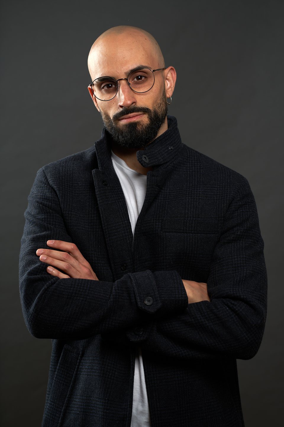 Con gafas y brazos cruzados, abrigo oscuro